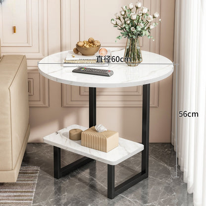 Round side table with lower shelf in a modern living room setting, suitable as a coffee table or bedside table. Ideal for wholesale buyers sourcing furniture directly from Chinese manufacturers, with options for customization. Decor elements like a vase and remote control highlight real-life usage.