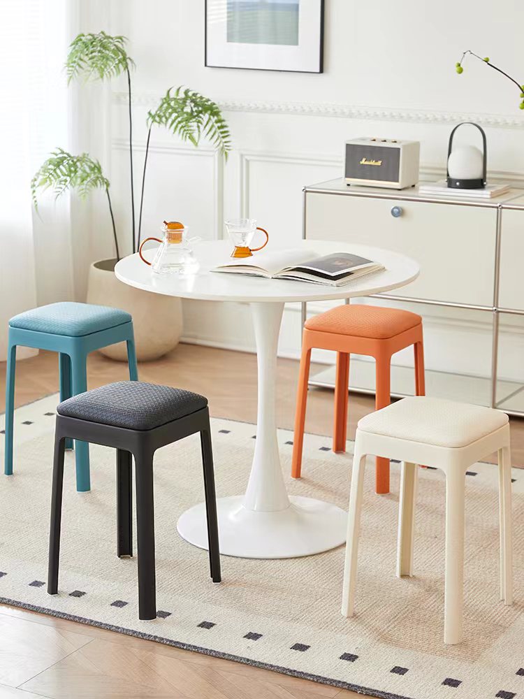 Stackable stools arranged around a dining table in a modern indoor setting, showcasing versatile seating options for cafes, offices, and collaborative spaces, available for direct wholesale from China.