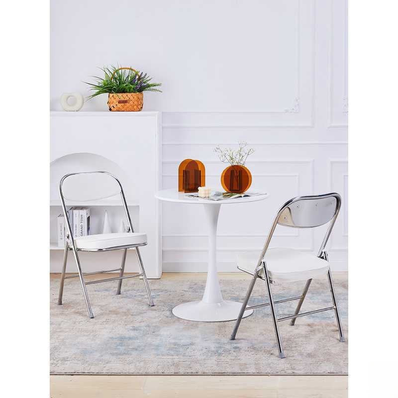 Small round dining table with foldable padded chairs and minimalist decor setup, suitable for cafes, dining rooms, or lounge areas. Perfect for bulk purchase and wholesale orders directly from China.