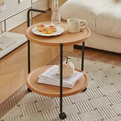 Two-tier round mobile coffee table in a cozy living room setting with books and decor, showcasing its versatile design and easy mobility. Ideal for wholesale buyers sourcing directly from China.