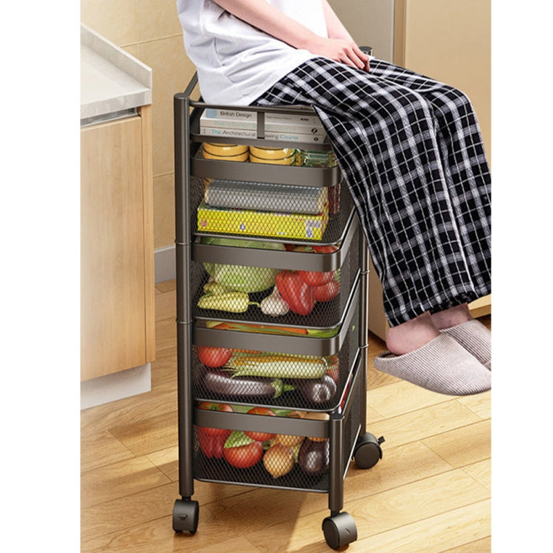 Person sitting on a multi-layered, movable storage rack filled with fruits and vegetables in a kitchen setting, showcasing the cart’s mobility and versatility. Ideal for bulk buyers sourcing wholesale from China for kitchen organization and storage solutions.