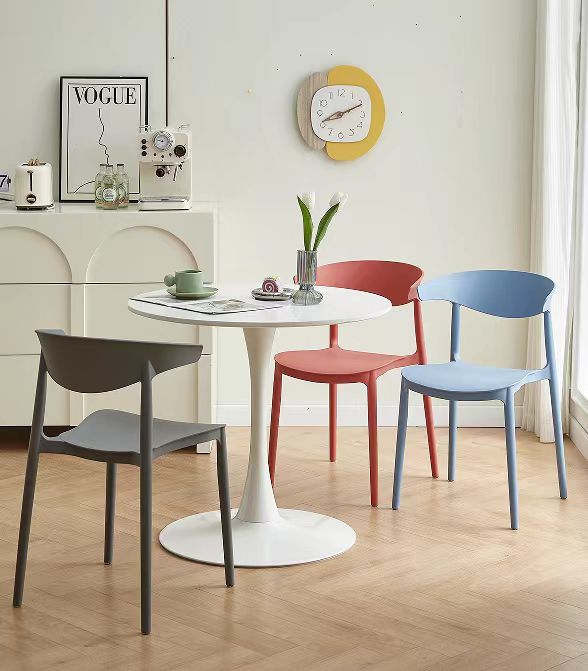 Modern multifunctional dining chairs around a round table in a contemporary dining room setting, showcasing stackable and space-saving design. Ideal for home, office, or commercial use, available for wholesale direct from China.