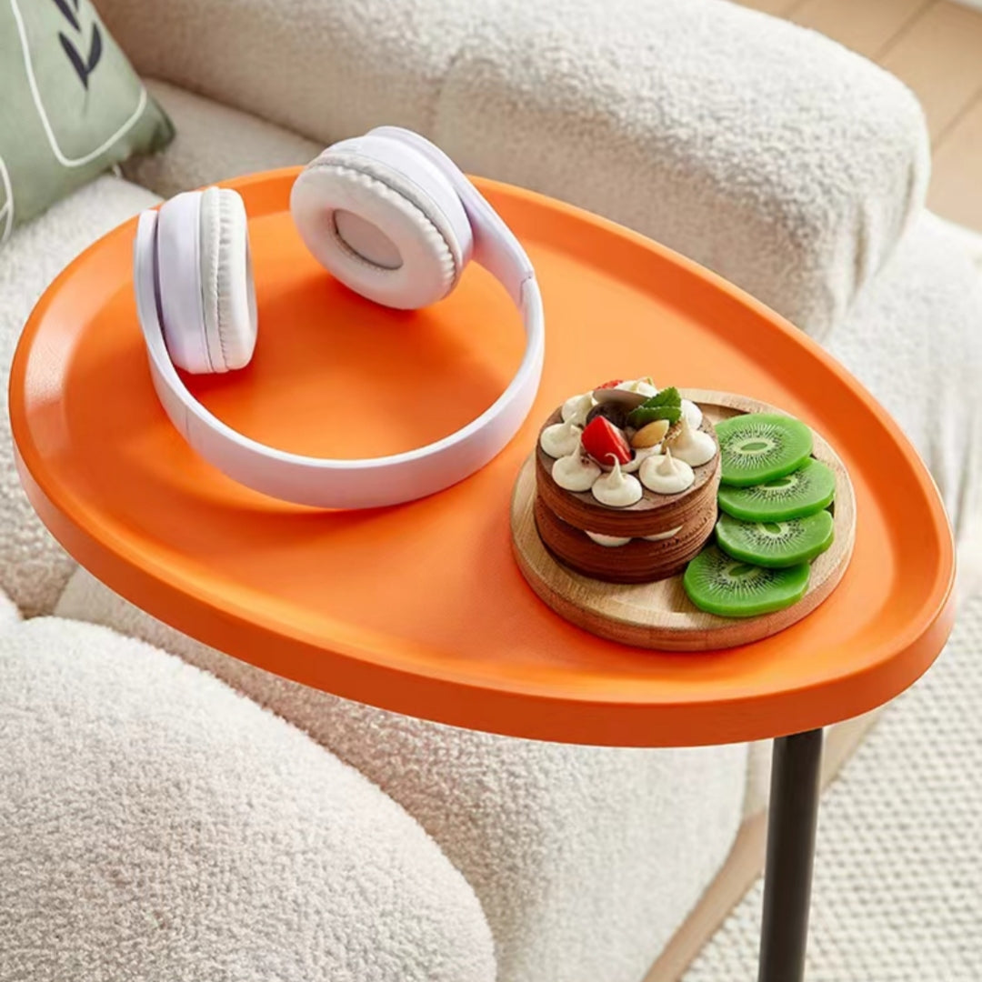 Oval-shaped versatile side table holding desserts and headphones, suitable for living rooms or home offices, ideal for wholesalers seeking affordable furniture solutions directly from China.